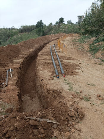 Rasa oberta enmig d'un terreny amb canonades de Tubverd a punt per instalar a la dreta i tanques d'obra