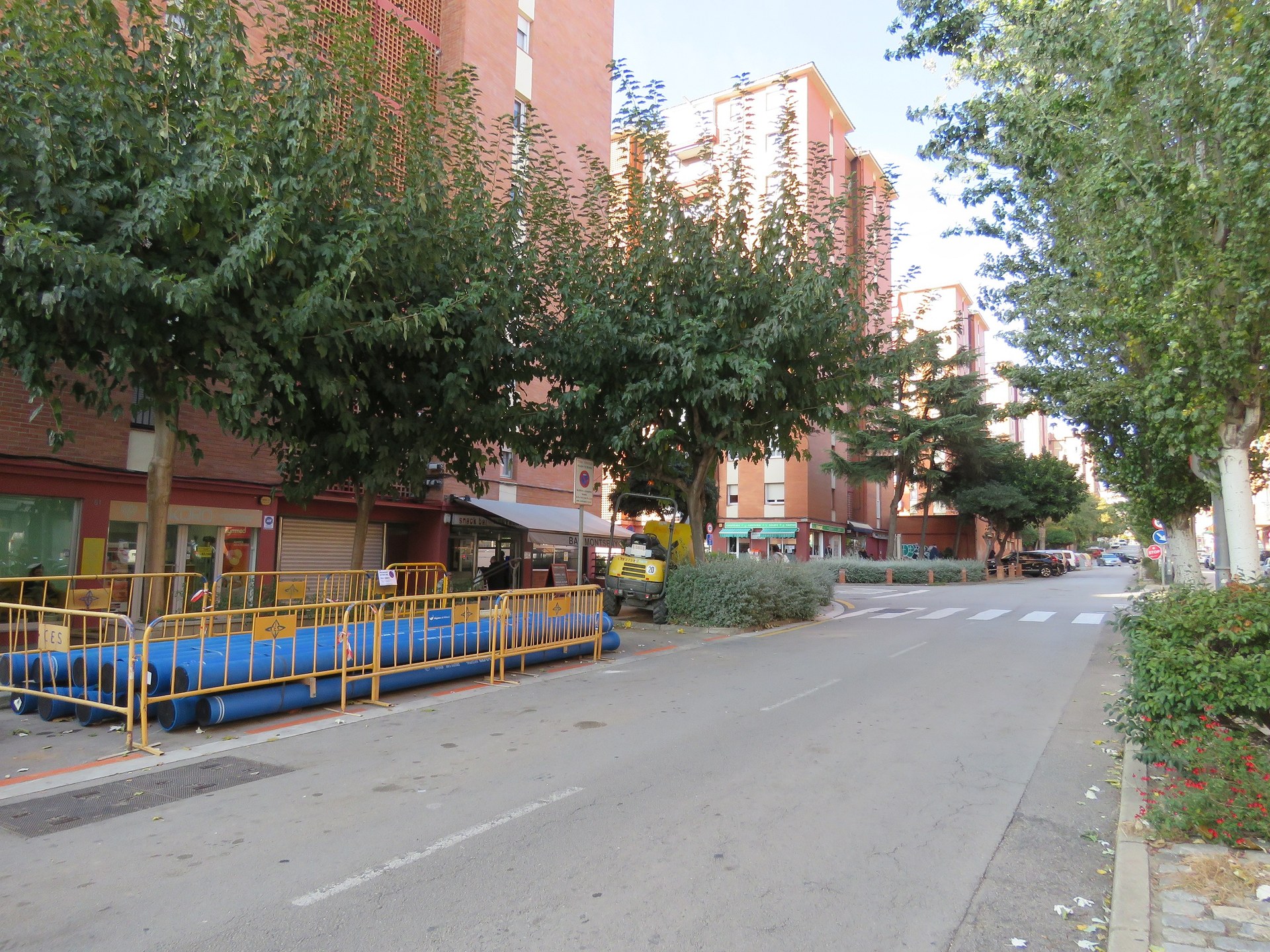 Roda de Francesc Macià amb canonades de color blau apilonades en un lateral del carrer i protegides amb tanques d'obresg