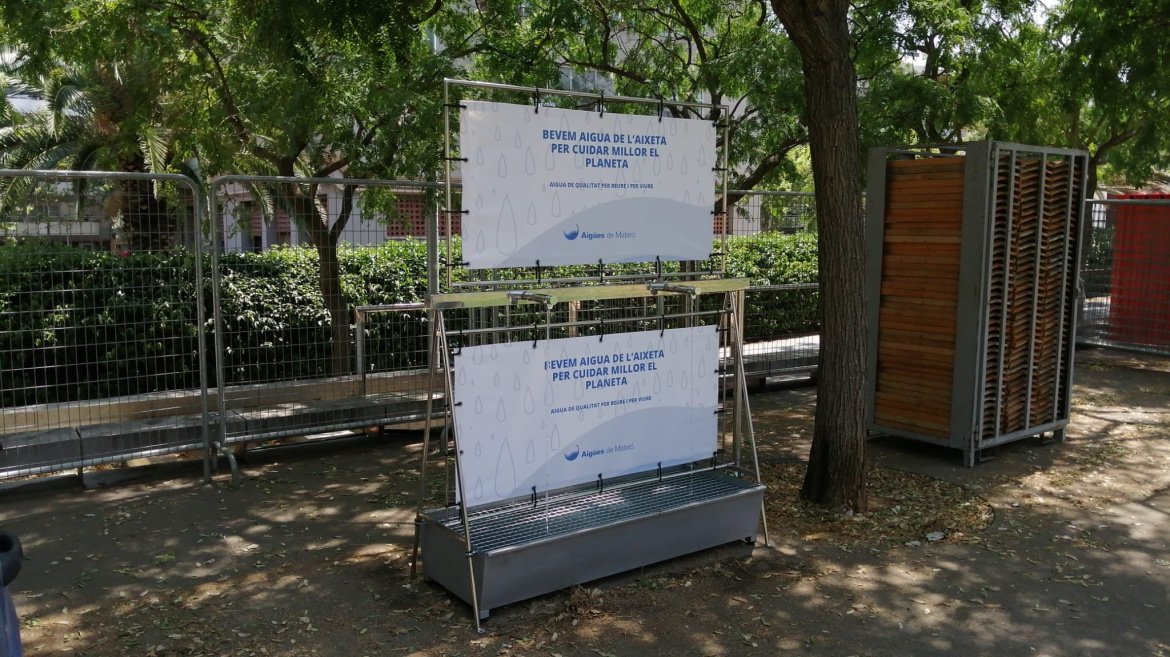 Font amb dues aixetes situada al Parc Central amb dues pancartes amb el lema "Bevem aigua de l'aixeta per cuidar millor el planeta"