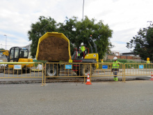 Operaris descarregant sorra amb una excavadora en rasa oberta al carrer