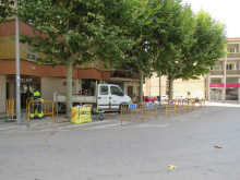Obres al carrer de Mossèn Ramon Fornells. Tanques d'obres al costat de la vorera, operari treballant i furgoneta de manteniment aparcada rere les tanques.