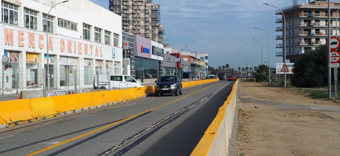 Cotxe circulant per l'avinguda del Maresme amb la Torre Barceló de fons