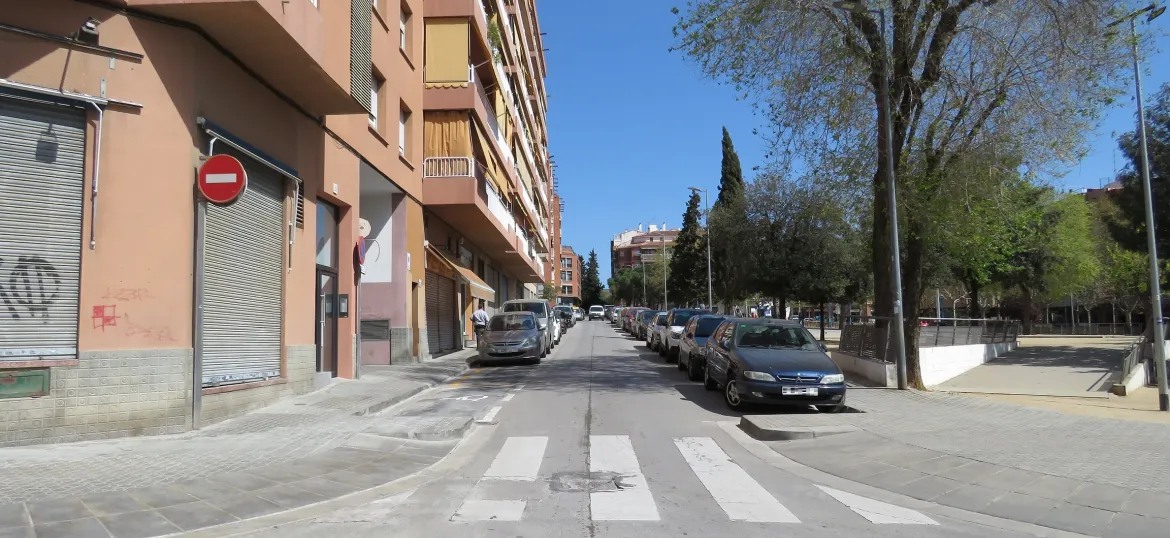 Pas de vianants amb cotxes aparcats als dos laterals de la vorera que envolta la Plaça de Catalunya