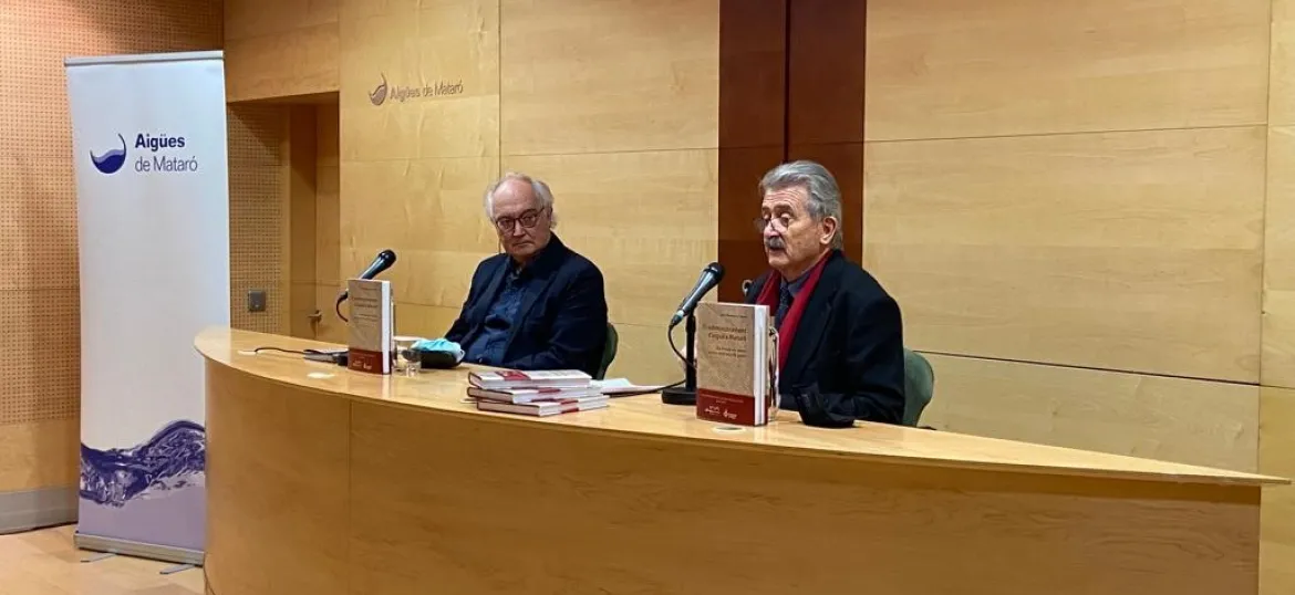 Manuel Mas i Estela i Rafael Montserrat i Barta al darrera d'un altril de fusta, presentant llibre del Centenari d'Aigües de Mataró