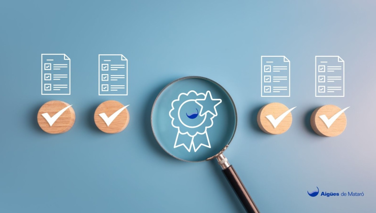 Imatge d'una lupa inspeccionant el logo d'AiGúes de Mataró i documents verificats
